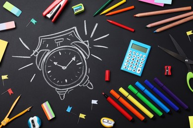 Photo of Flat lay composition with different stationery and drawn alarm clock on blackboard. School time