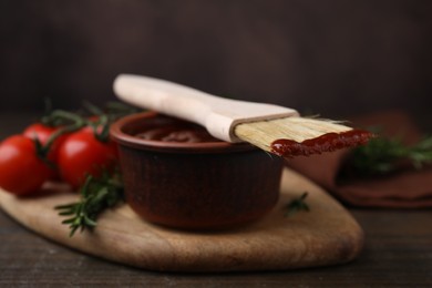 Photo of Marinade in bowl and basting brush on wooden table, closeup