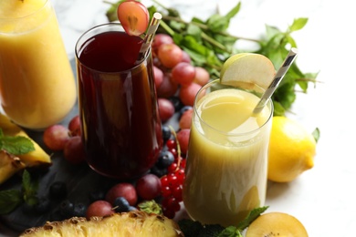 Glasses of delicious juices and fresh ingredients on table