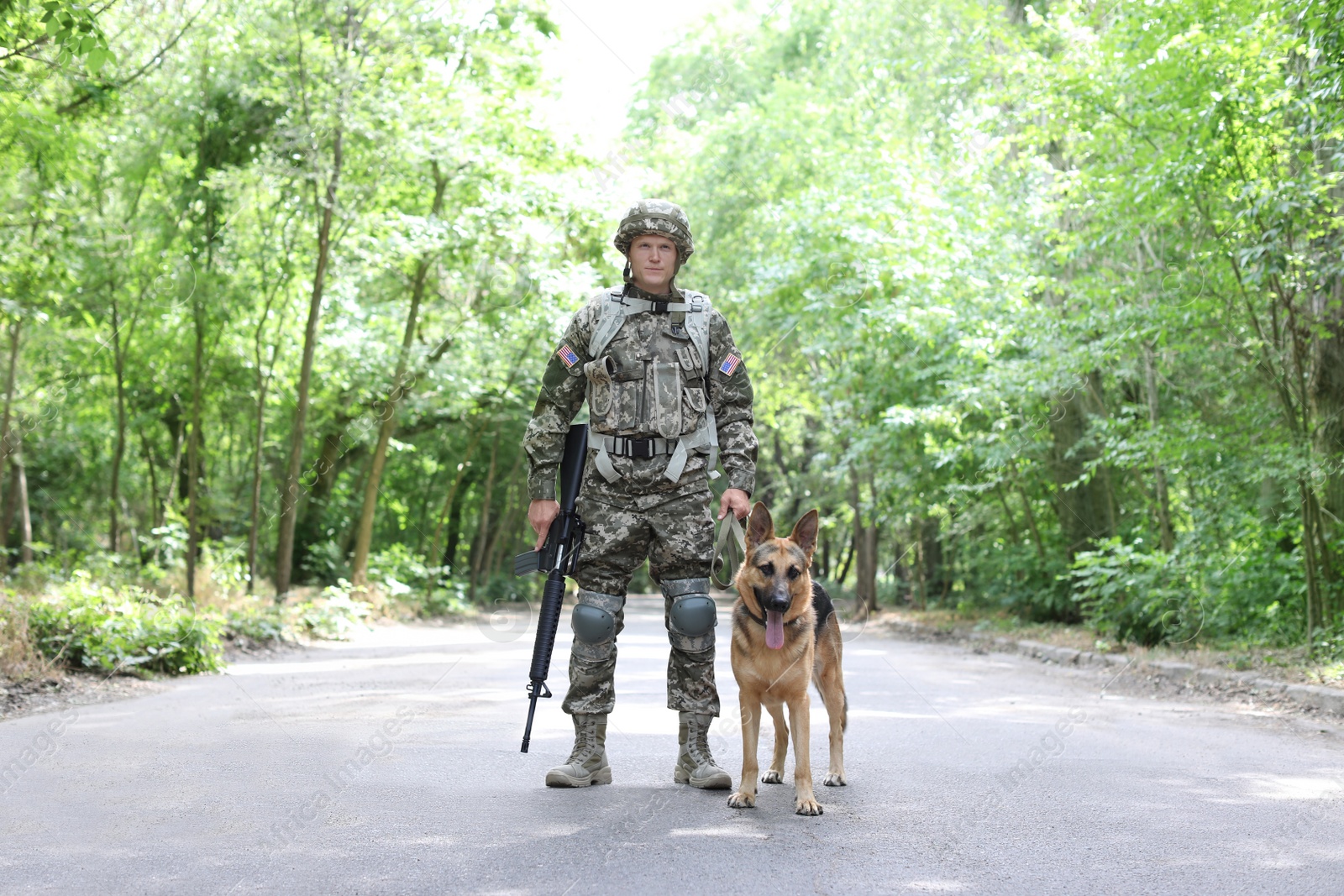 Photo of Man in military uniform with German shepherd dog, outdoors