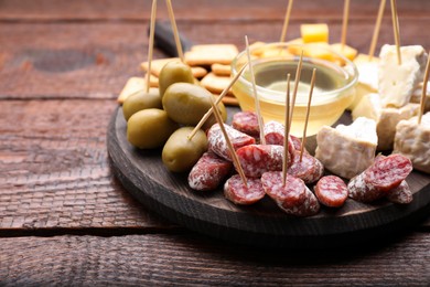 Photo of Toothpick appetizers. Pieces of sausage, cheese and honey on wooden table, space for text