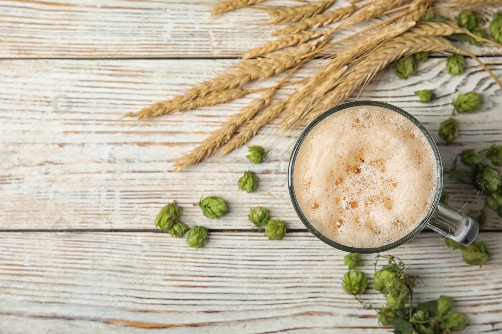 Photo of Flat lay composition with tasty beer, fresh green hops, wheat spikes and space for text on wooden background