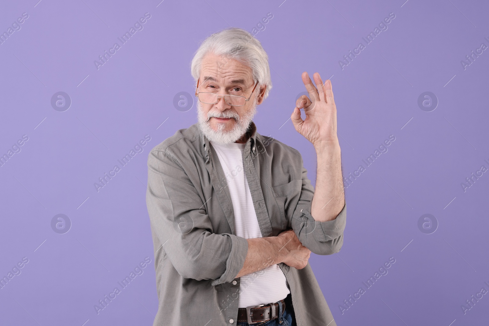 Photo of Portrait of stylish grandpa with glasses showing ok gesture on purple background