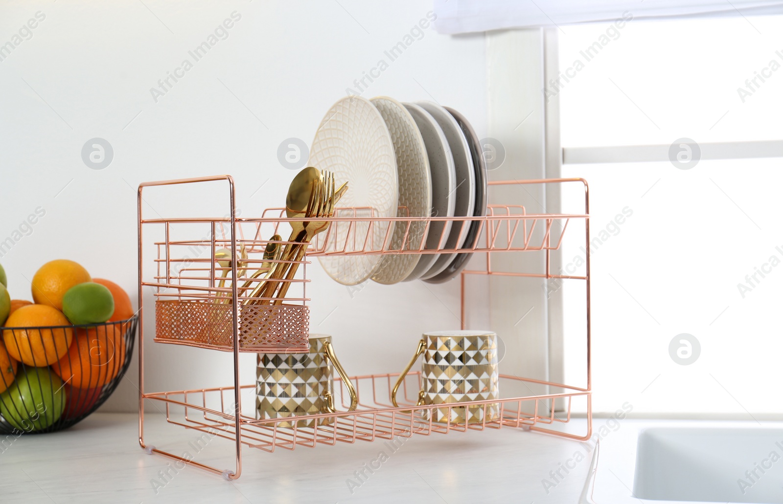 Photo of Clean dishes on drying rack in modern kitchen interior