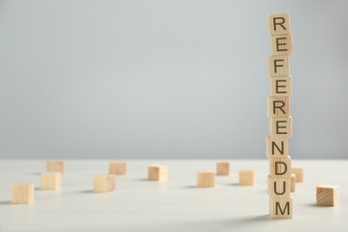 Photo of Word Referendum of wooden cubes on white table against light grey background. Space for text
