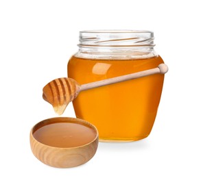 Natural honey dripping from dipper into wooden bowl. Jar full of honey on white background