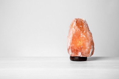 Himalayan salt lamp on table against light background