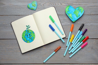 Photo of Happy Earth Day. Flat lay composition with notebook and markers on grey wooden table