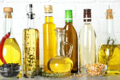 Photo of Different cooking oils in bottles on grey table