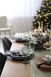 Christmas table setting with festive decor and dishware in room