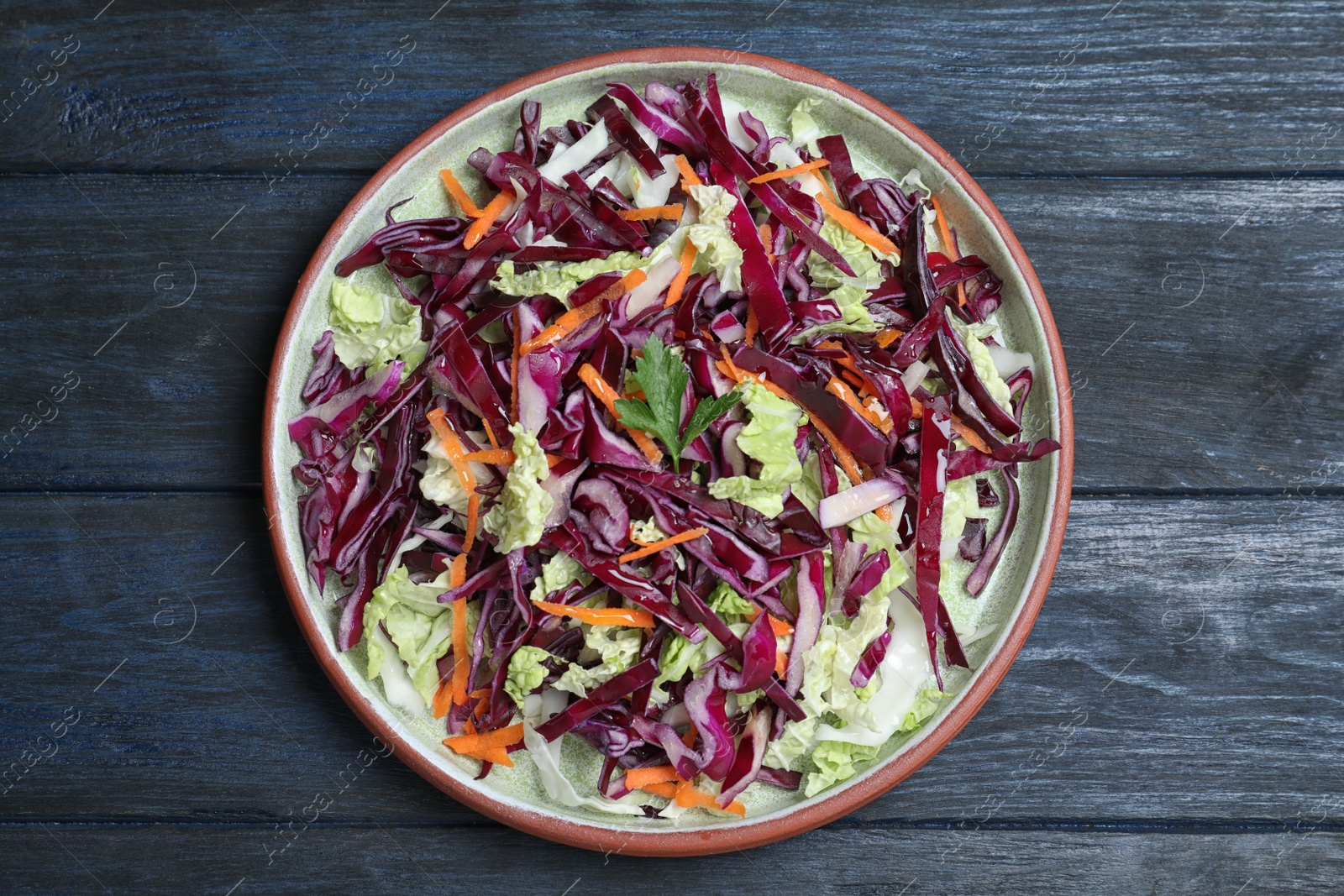 Photo of Fresh cabbage salad served on blue wooden table, top view