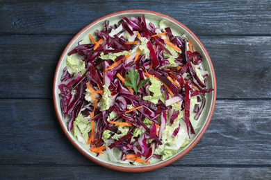 Photo of Fresh cabbage salad served on blue wooden table, top view