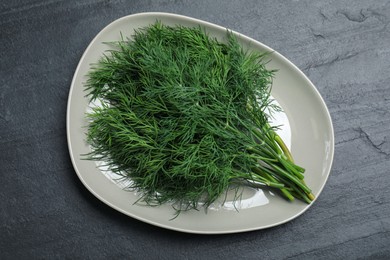 Photo of Plate of fresh dill on black table, top view