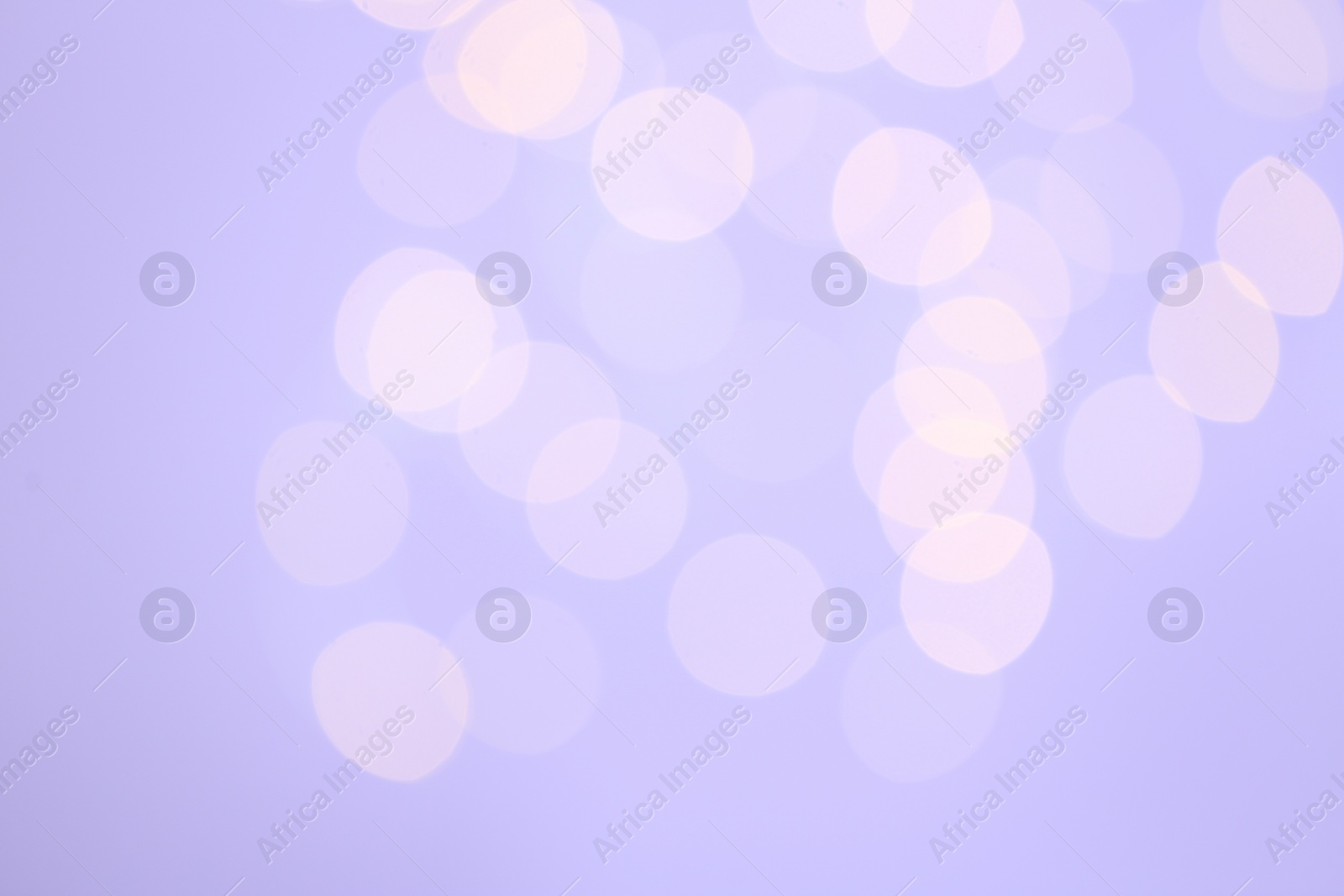 Photo of Blurred view of festive lights on lilac background. Bokeh effect
