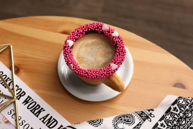 Photo of Delicious edible biscuit cupcoffee decorated with sprinkles on wooden table, above view