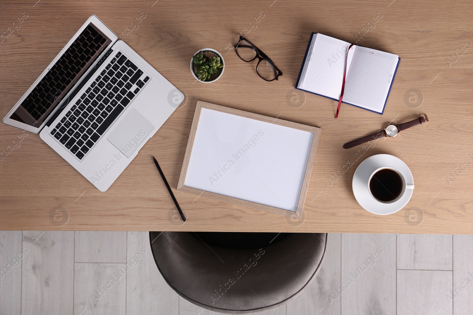 Photo of Chair near wooden table with laptop, cup of coffee and stationery indoors, top view