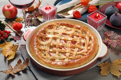 Photo of Delicious homemade apple pie and autumn decor on wooden table. Thanksgiving Day celebration