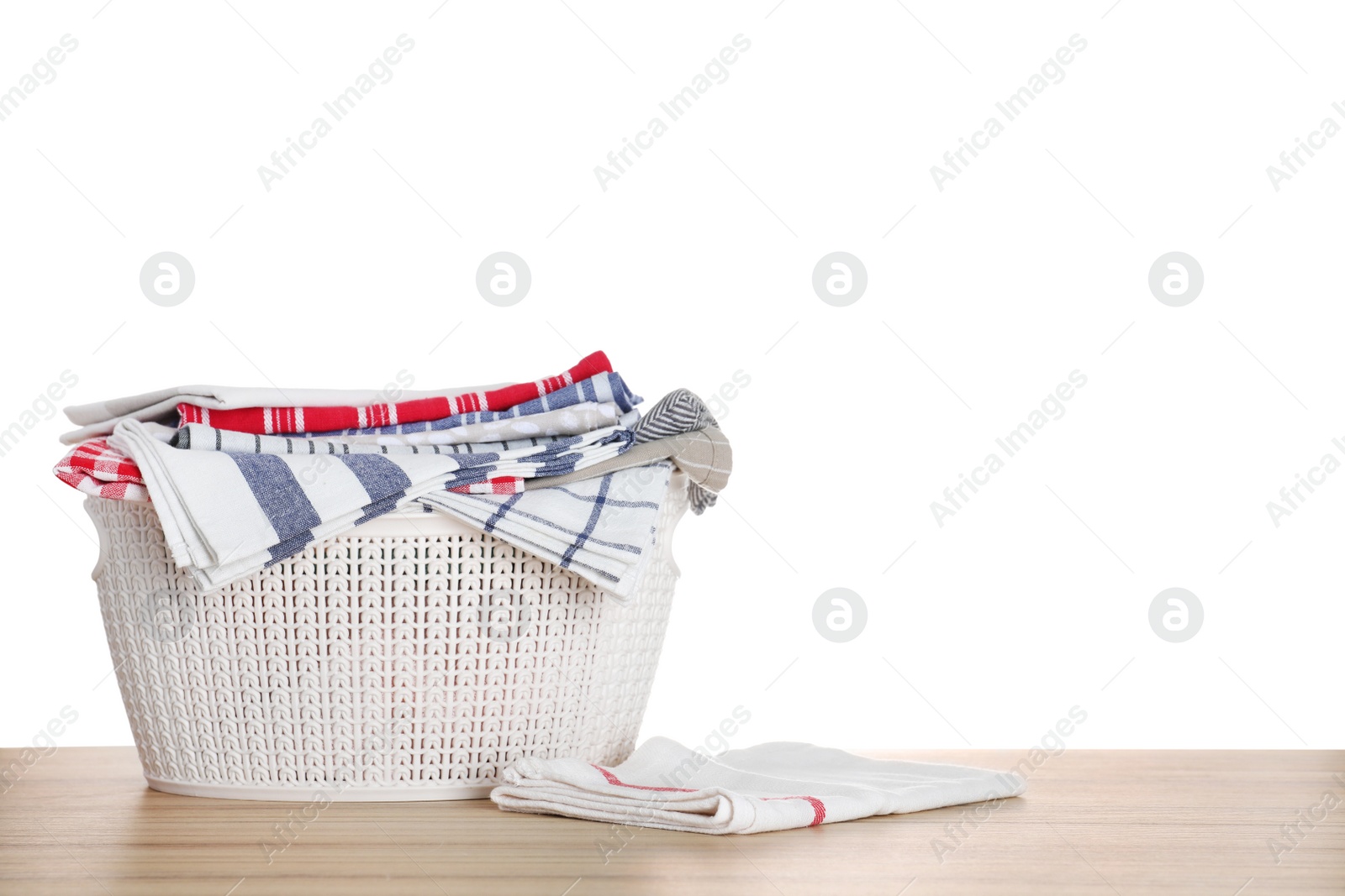 Photo of Basket with clean laundry on wooden table, white background