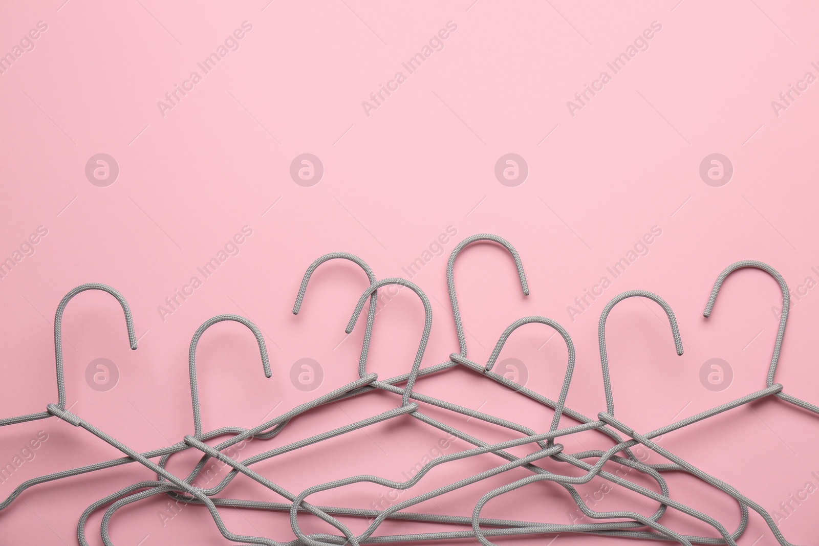 Photo of Hangers on pink background, flat lay. Space for text