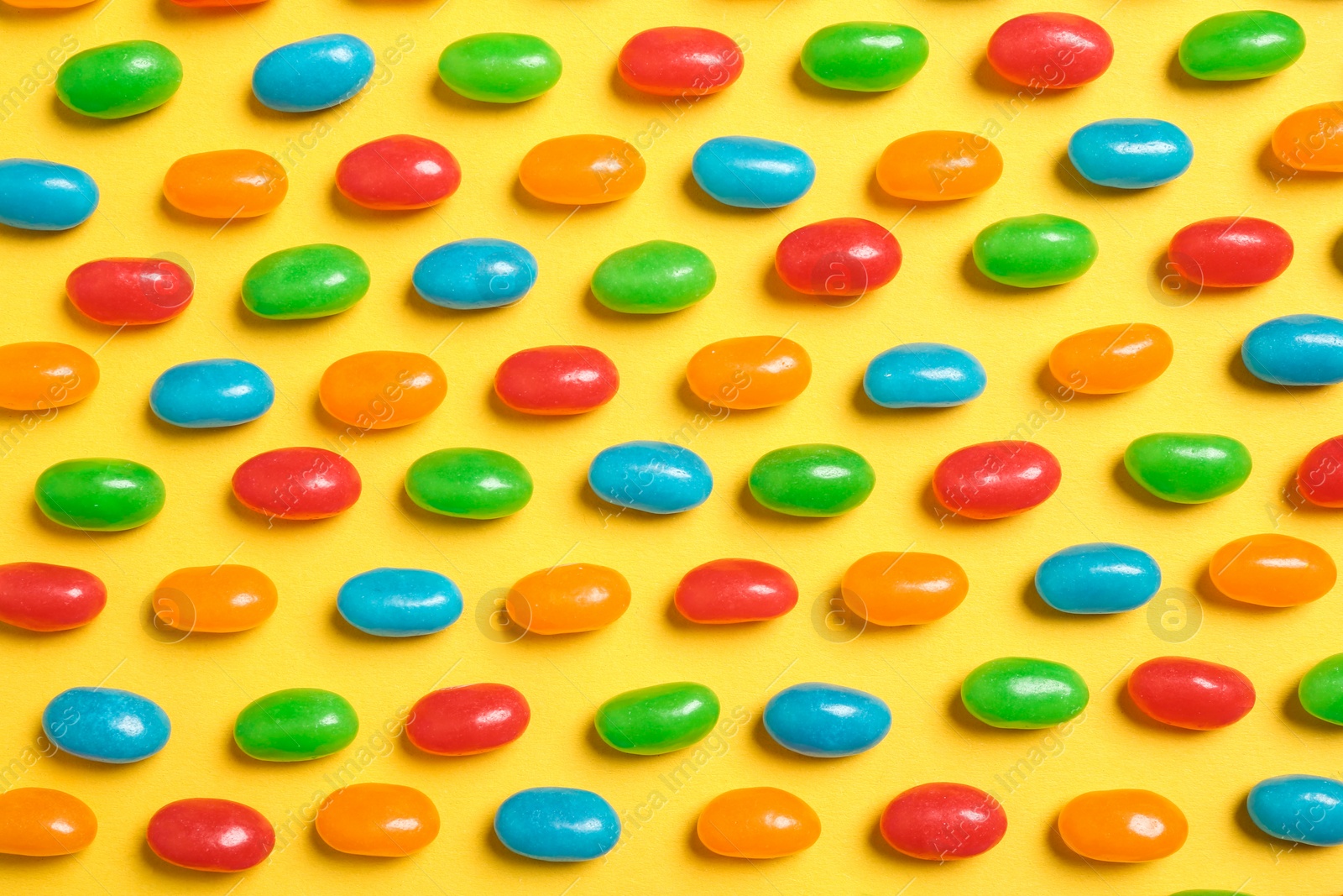 Photo of Flat lay composition with delicious jelly beans on color background