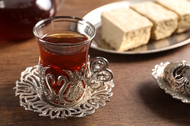 Glass of traditional Turkish tea in vintage holder on wooden table, closeup. Space for text