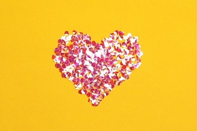 Heart made with shiny glitter on orange background, flat lay