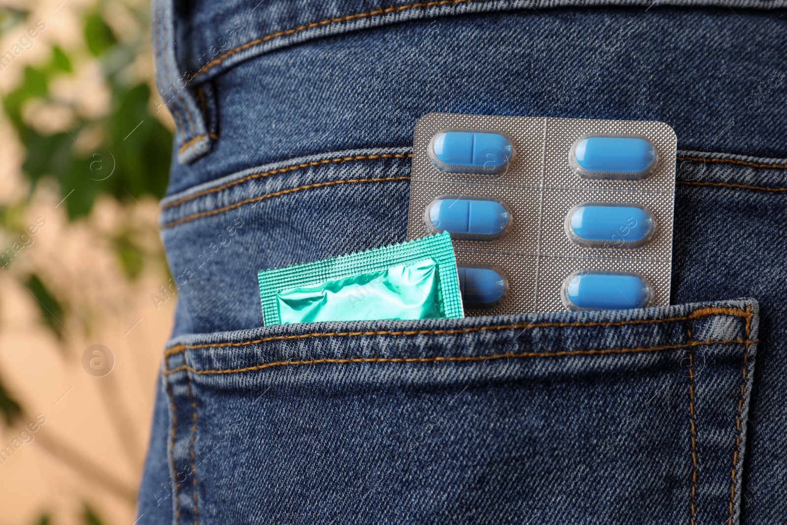 Photo of Jeans with pills and condom in pocket, closeup. Potency problem