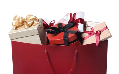 Photo of Dark red paper shopping bag full of gift boxes on white background, closeup