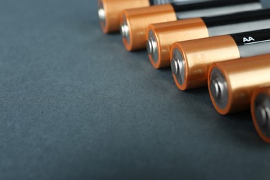 Image of New AA batteries on dark background, closeup. Space for text