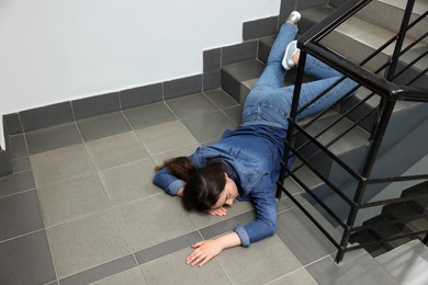 Photo of Unconscious woman lying on floor after falling down stairs indoors, space for text