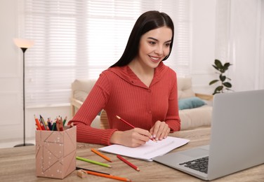 Photo of Happy woman drawing picture at online art lesson indoors. Distant learning