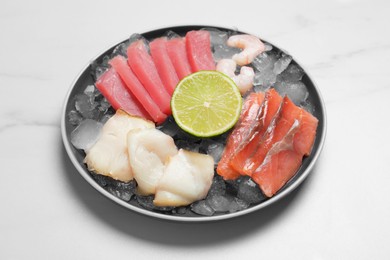 Photo of Sashimi set (raw slices of tuna, salmon, oily fish and shrimps) served with lime and ice on white marble table