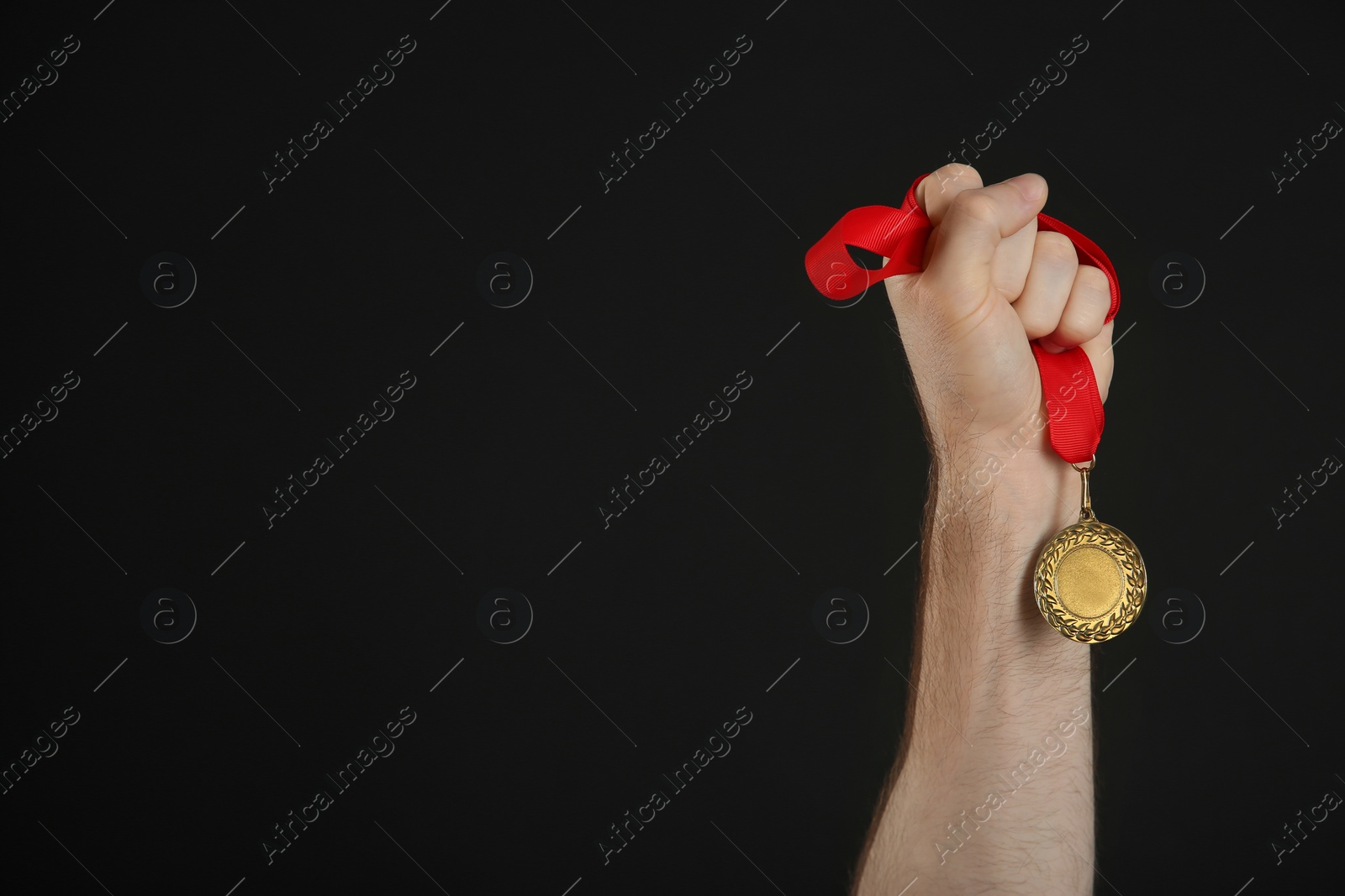 Photo of Man holding golden medal on black background, closeup. Space for design