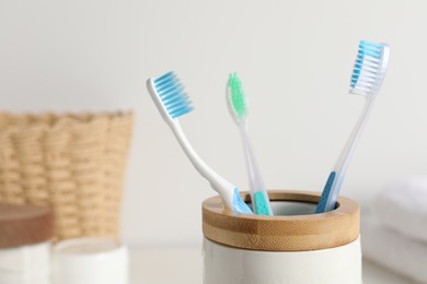 Plastic toothbrushes in holder on blurred background, closeup