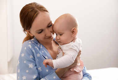 Photo of Young woman with her little baby resting after breast feeding on bed