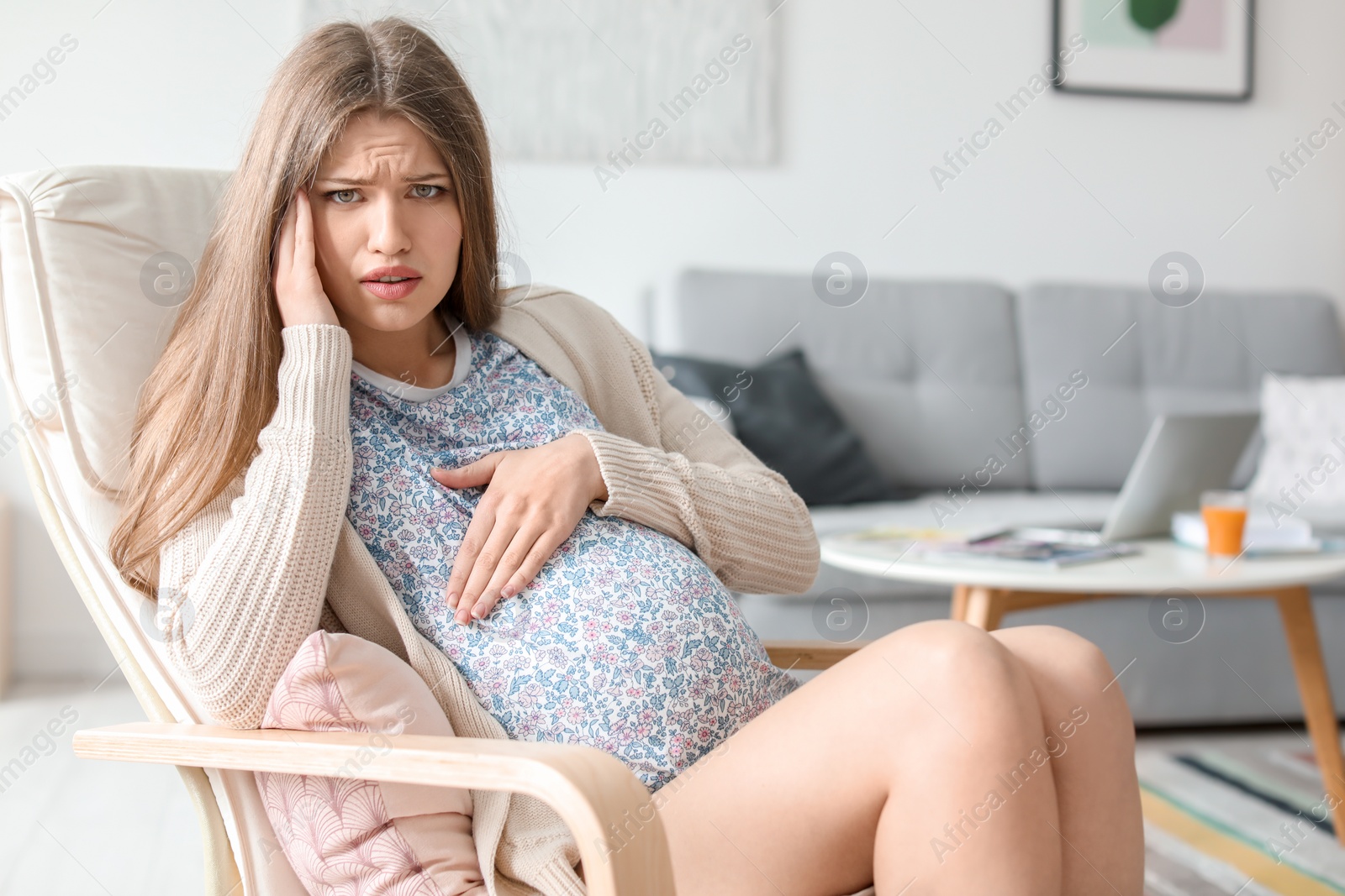 Photo of Young pregnant woman suffering from headache at home
