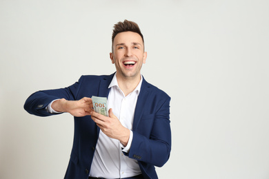 Photo of Happy man throwing money on light grey background. Space for text