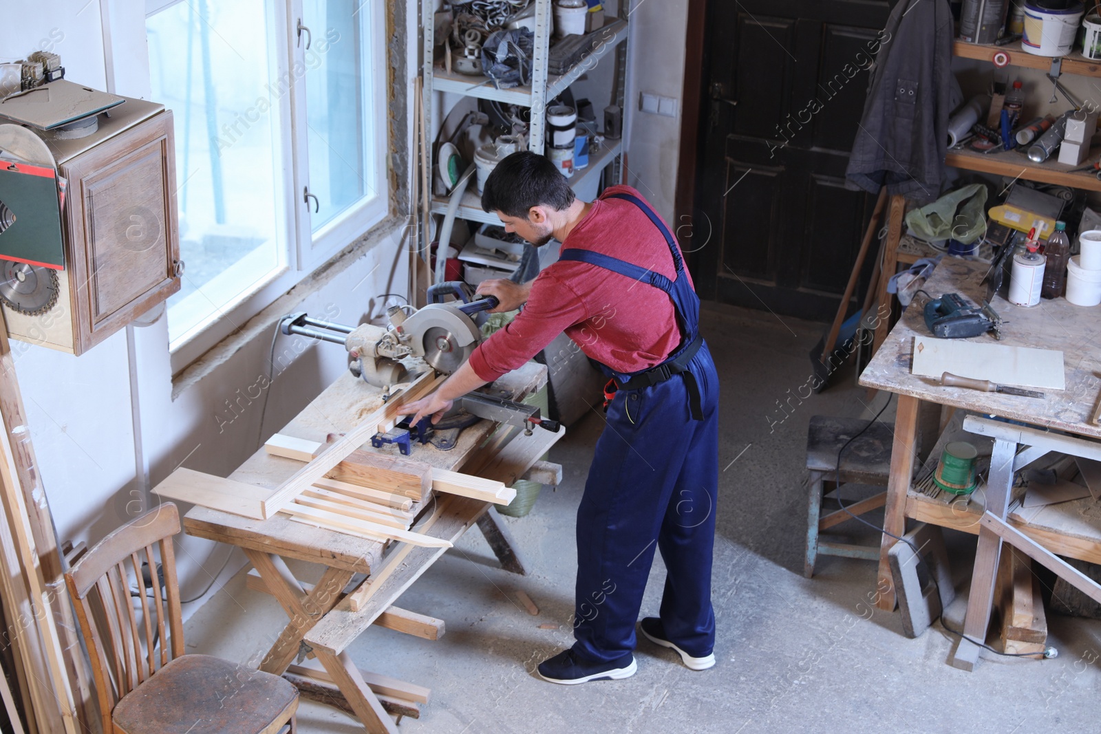 Photo of Mature working man using circular saw at carpentry shop, above view