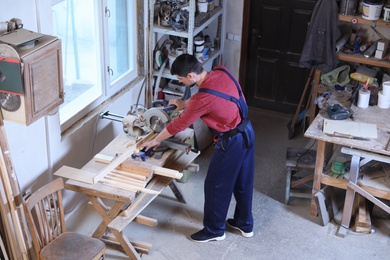 Photo of Mature working man using circular saw at carpentry shop, above view