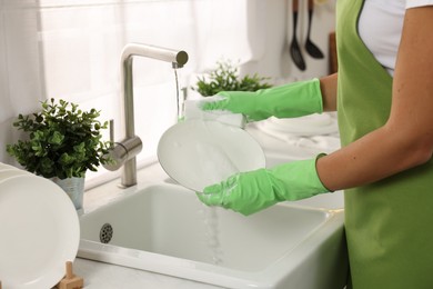 Photo of Woman washing plate at sink in kitchen, closeup