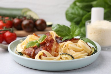 Tasty pasta with bacon and basil on light grey table