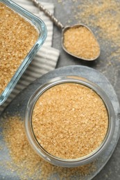 Photo of Brown sugar and spoon on grey table, flat lay