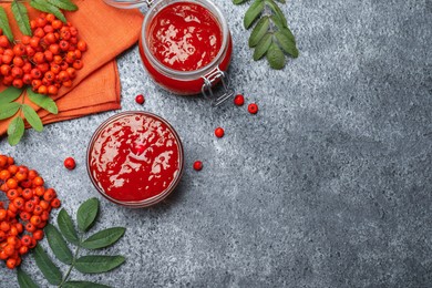 Flat lay composition with delicious rowan jam and berries on grey table. Space for text