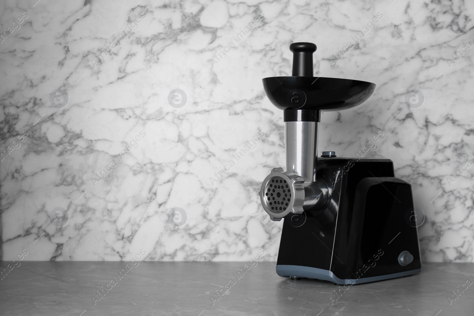 Photo of Modern electric meat grinder on grey table. Space for text