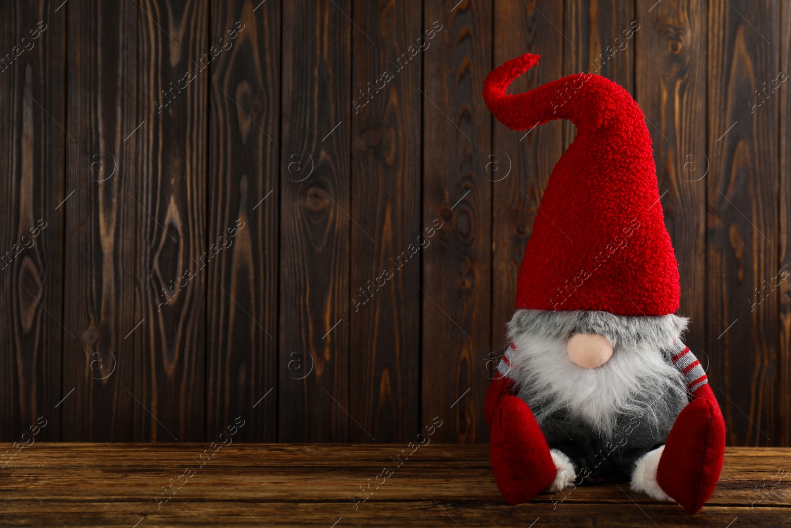 Photo of Cute Christmas gnome on wooden table. Space for text