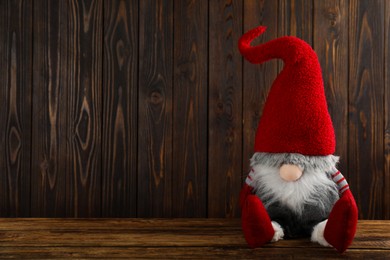 Photo of Cute Christmas gnome on wooden table. Space for text