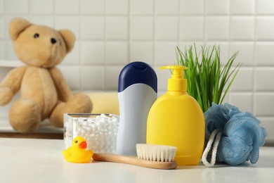 Baby cosmetic products, bath duck, brush and cotton swabs on white table