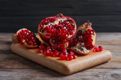 Board with ripe pomegranates and seeds on wooden table