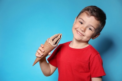 Adorable little boy with delicious ice cream against color background, space for text