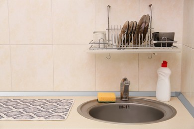 Clean dishware on drying rack over sink in kitchen, space for text